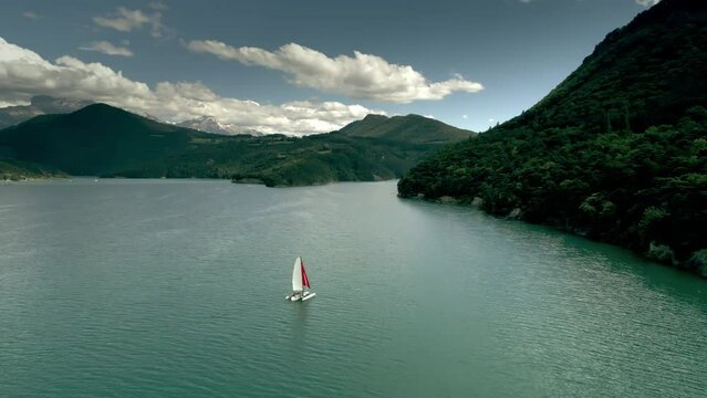 Aerial shot of a sailboat or trimaran with the red sail on the Lake of Monteynard-Avignonet, French Alps, France