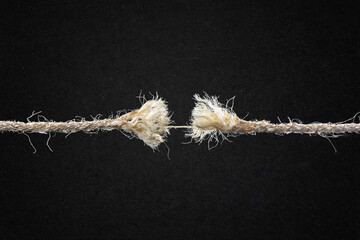 Frayed Rope About to Break Against Textured Black Paper Background with Copy Space