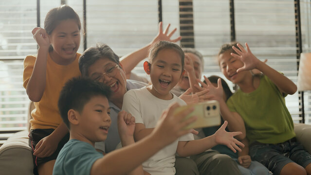 happy multi generation lifestyle concept asian grandparent and grand children taking selfie smartphone together on sofa in living room daylight at home smiling cheerful asian family visit grand parent
