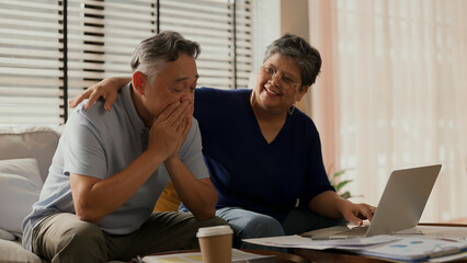 old retired asian senior couple checking and calculate financial billing together on sofa involved...