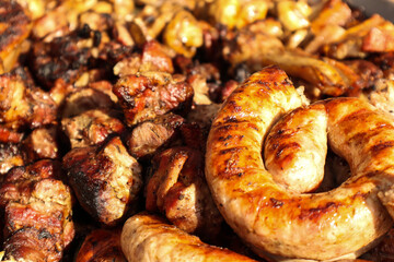 Street food: pieces of meat and sausage on the grill, close-up