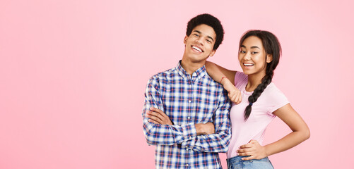 Happy african-american couple posing on pink studio background