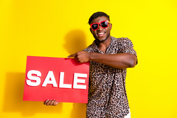 Photo of cheerful nice man wear stylish clothes showing banner summer sale isolated on yellow color...