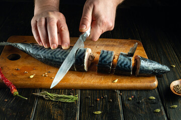 Chef hands using a knife to cut mackerel fish into pieces to prepare a dish for lunch. Fish diet concept.