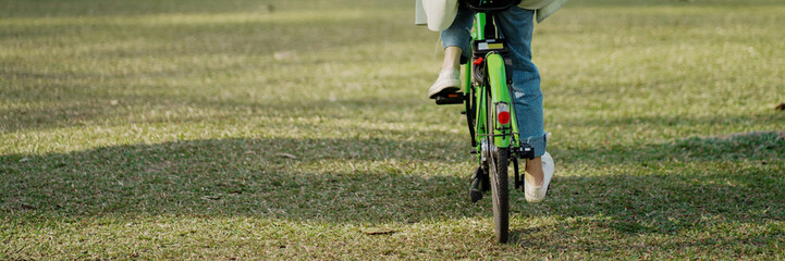 Happy asian woman riding bicycle on public park.