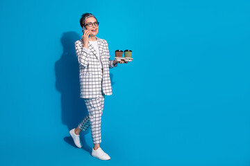Fototapeta premium Photo of cheerful successful woman wear white stylish clothes walk carry coffee empty space isolated on blue color background