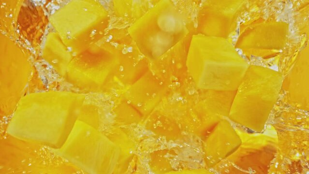 Super Slow Motion of Falling Mango Slices into Water, Colored Background. Filmed on High Speed Cinema Camera, 1000 fps. Camera Tracking the Target.