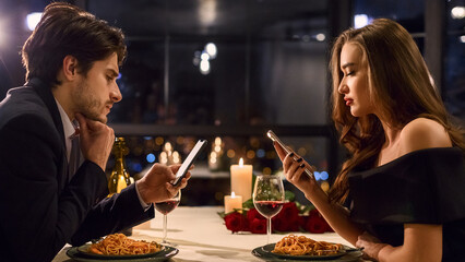 Man and woman do not communicate to each other and using their smartphones during dating at luxury restaurant