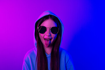 Photo of cheerful funny little lady dressed hoodie dark glasses stick out empty space isolated neon purple color background