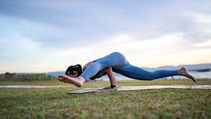 Fototapeta premium A woman doing yoga on a grassy field