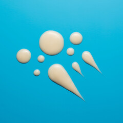 Arrangement of creamy-white droplets and smears against azure background