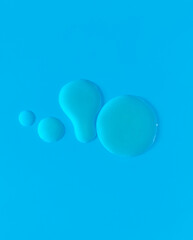 Refreshing droplets and dabs of hydrating clear skincare gel set against bright blue background, emphasizing clarity and purity of cosmetic product. Abstract minimalist composition