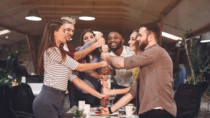 Unity concept. Colleagues putting their fists together at workplace