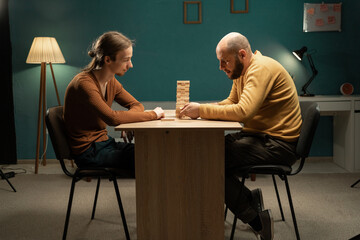 friends playing board game with wooden blocks, strategy game at home at table. Hobby and home life