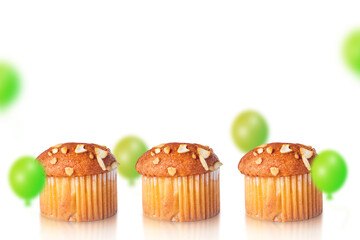 Muffins and green balloons on white background with space for text.