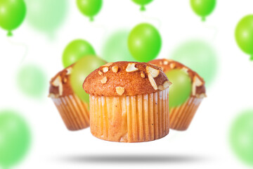 Muffins and green balloons flying on white background for birthday celebration. Closeup