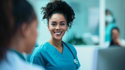 Smiling female nurse in blue scrubs with stethoscope around neck standing in a hospital setting.