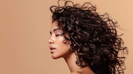beauty portrait of a young woman with healthy curly hair and natural skin without makeup, on a beige background, skin and curly hair care concept