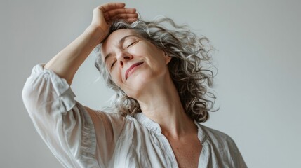 Naklejka premium Woman with gray hair smiling with hand on head wearing white blouse against white background.