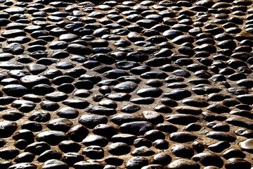 Background, texture of the road paved with cobblestones polished to a shine by the feet of passers-by