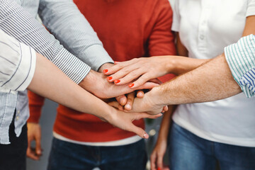 Cropped of diverse group of individuals of different ages and ethnicities coming together in unity and solidarity. They are standing in a circle, each extending their hands towards the center