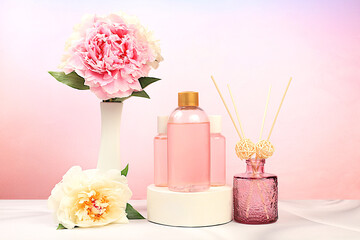 Lotion bottles with rose extracts and peony flowers on elegant background, natural organic cosmetics concept, spa and store advertising, minimal composition, selective focus.