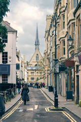 Obraz premium English street with Gothic architecture church spire and pedestrians capturing the charm of urban life and cultural richness, travel and lifestyle, focusing on historic beauty and city exploration