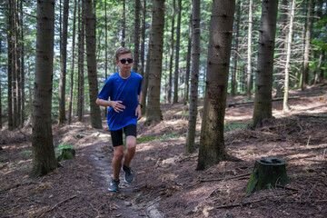 A young man runs along a path in the forest.