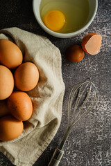 foto superior com cesta de ovos inteiros ao lado de um ovo fresco quebrado em fundo cinza com textura. sem ninguém.