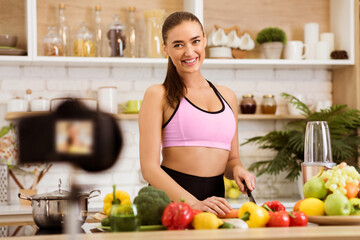 A woman in athletic wear prepares a healthy meal in her kitchen, filming the process for her online cooking show.