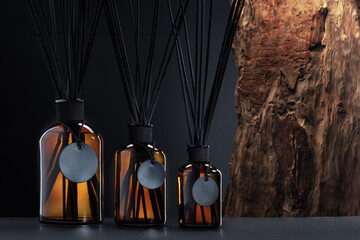 Trio of elegant aroma diffusers with black reeds on wooden background