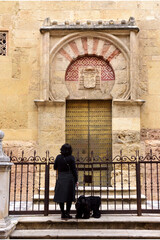 Obraz premium tourist front of Door and facade San Miguel, Moorish facade of the Great Mosque in Cordoba, Andalusia, Spain