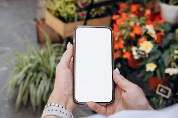 Blank smartphone screen , smartphone in a woman's hand in the background of a flower store, mock up delivery app 