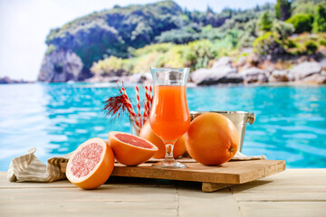 Fresh citrus fruit on wooden table top with beautiful summer landscape of calm sea and blue sky.