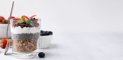 Tasty dessert with granola, yogurt, chia seeds and berries on white table. Banner design with space for text