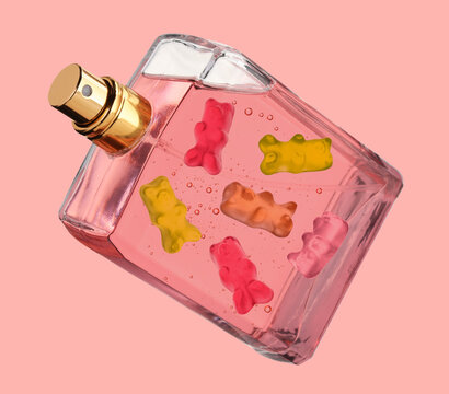 Perfume bottle with sweet gummy bears inside on coral color background, creative collage