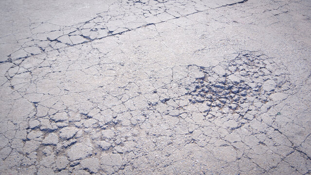 Cracks and broken texture on surface of the old badly damaged concrete street surface