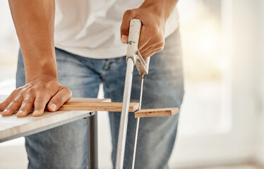 Hands, wood and saw with person in home for building, construction or DIY project closeup....