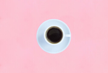 Black coffee in the white cup on the pink background. Copy space. Top view.