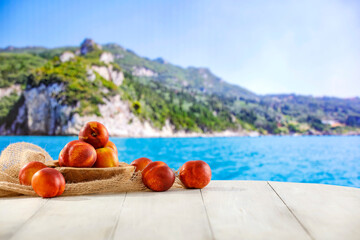 Fresh fruit on wooden table top with exotic landscape of fruit gardens and plantations. Natural...