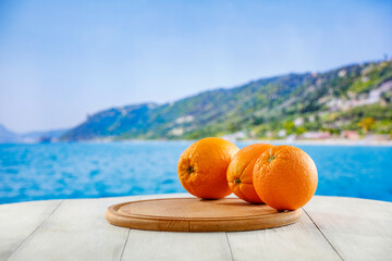Fresh citrus fruit on wooden table top with beautiful summer landscape of calm sea and blue sky.