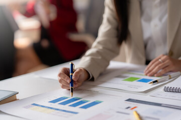 Business professional analyzing financial charts and data at office desk during a meeting, focusing on growth and strategy.