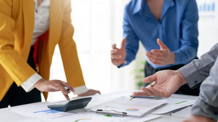 Business team discussing financial report. Close-up of hands, documents, and calculator on office desk during meeting.