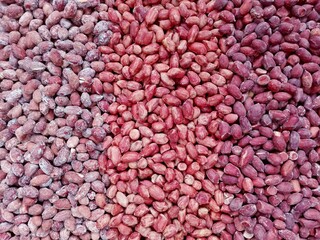 Peanut snack texture background. Closeup red peanut, roasted groundnut snack. Eating peanuts snack concept macro. Peeled groundnut heap in shop background. Salted pea nuts with skin above, top view