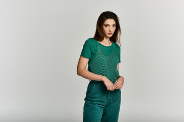 A young woman in a stylish green outfit stands against a white background.