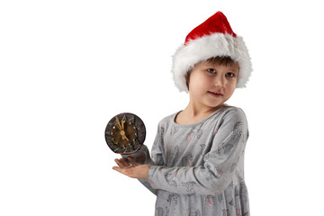 Naklejka premium A child wearing a Santa Claus hat holds a clock showing 5 minutes to midnight. Png. Copy space.