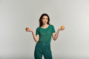 A young woman in a green outfit holds two peaches in her outstretched hands.