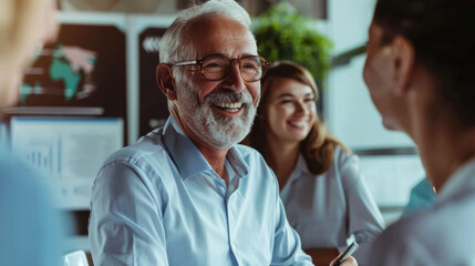 Obraz premium A lively business meeting with colleagues sharing a joyful moment, featuring an elderly man with a big smile, ensuring a positive and productive environment.