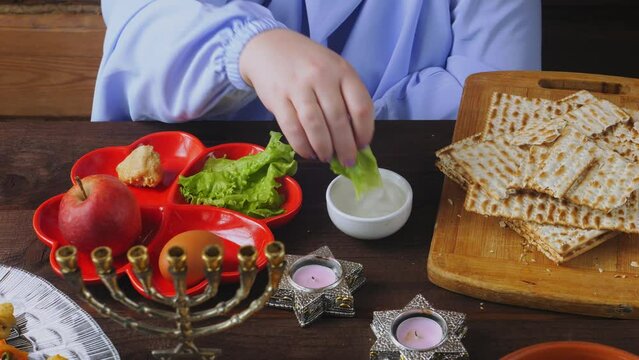 Jewish woman eating maror with matzoh meal Pesach Seder. Medium plan.