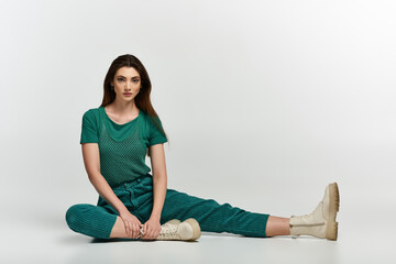 Young woman exudes confidence in emerald green attire on white background.